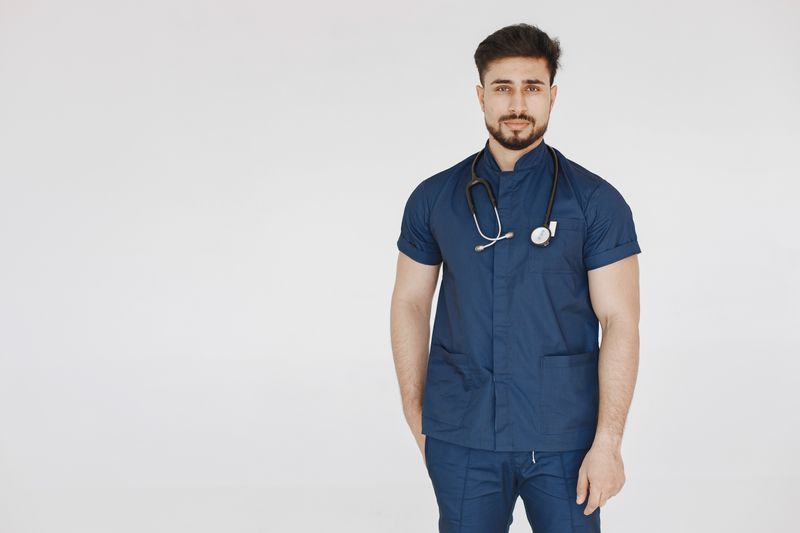Médico en uniforme azul con estetoscopio sonriendo