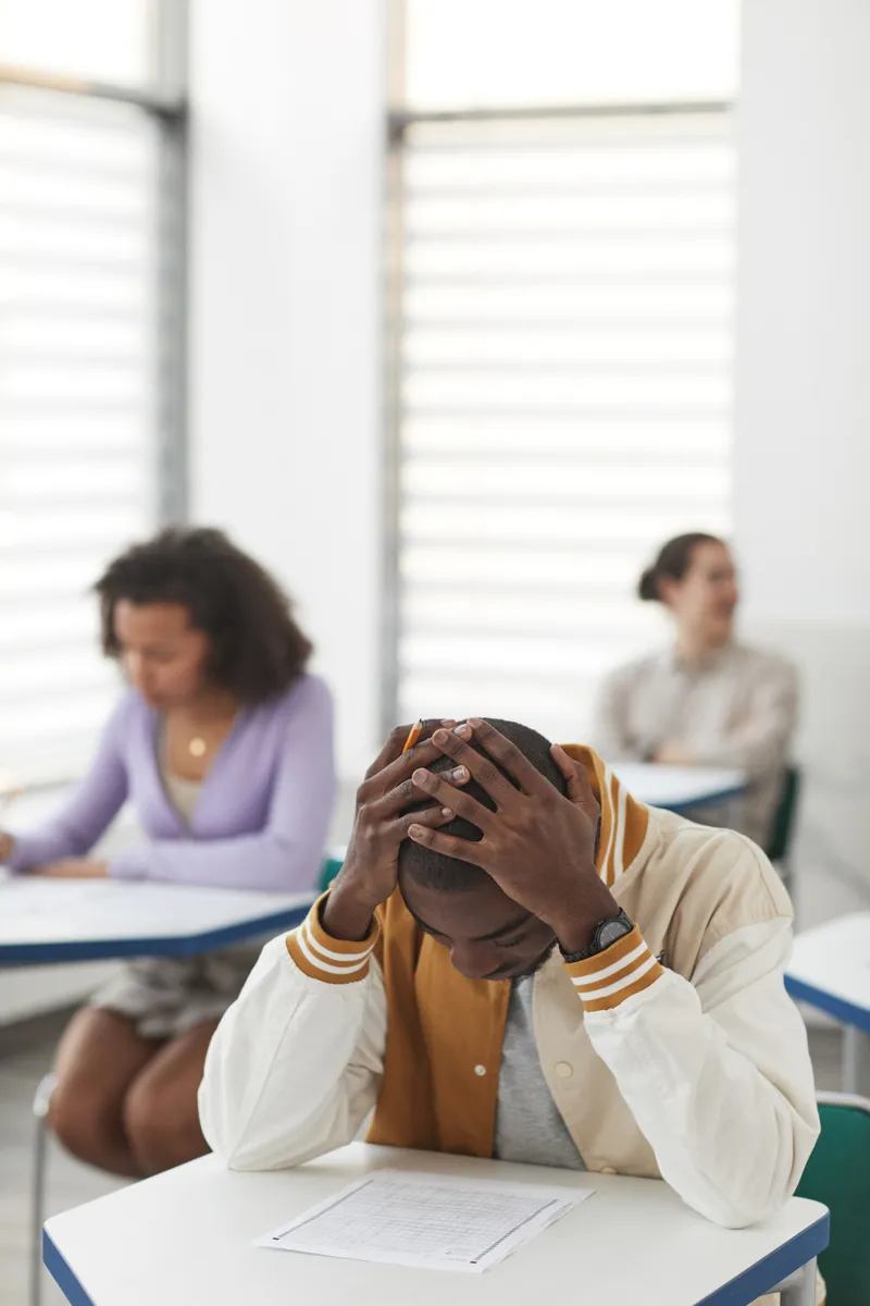 Joven estudiante estresado durante un examen en un salón de clases